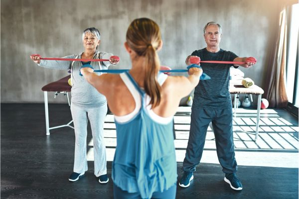 A personal trainer giving a private strength training session to an elder couple