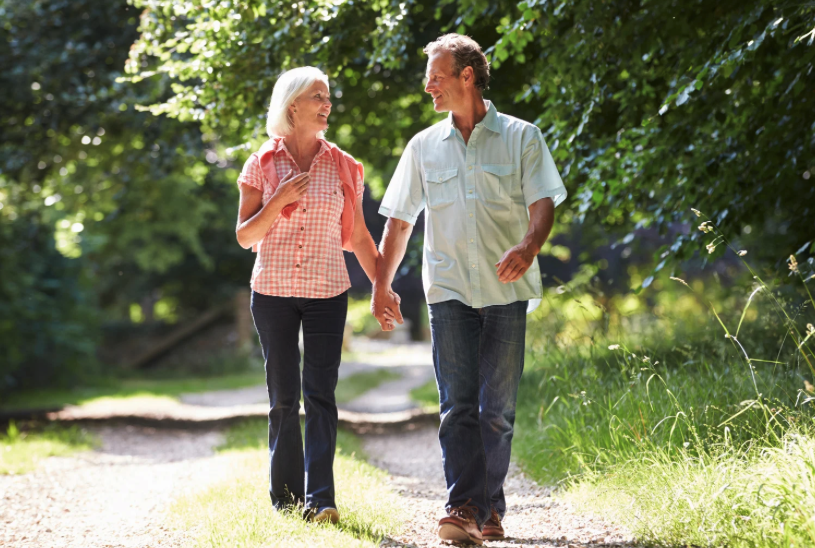 Older couple walking together on a nature trail, illustrating how light walking helps activate muscles and support healthy lymphatic circulation and fluid movement.