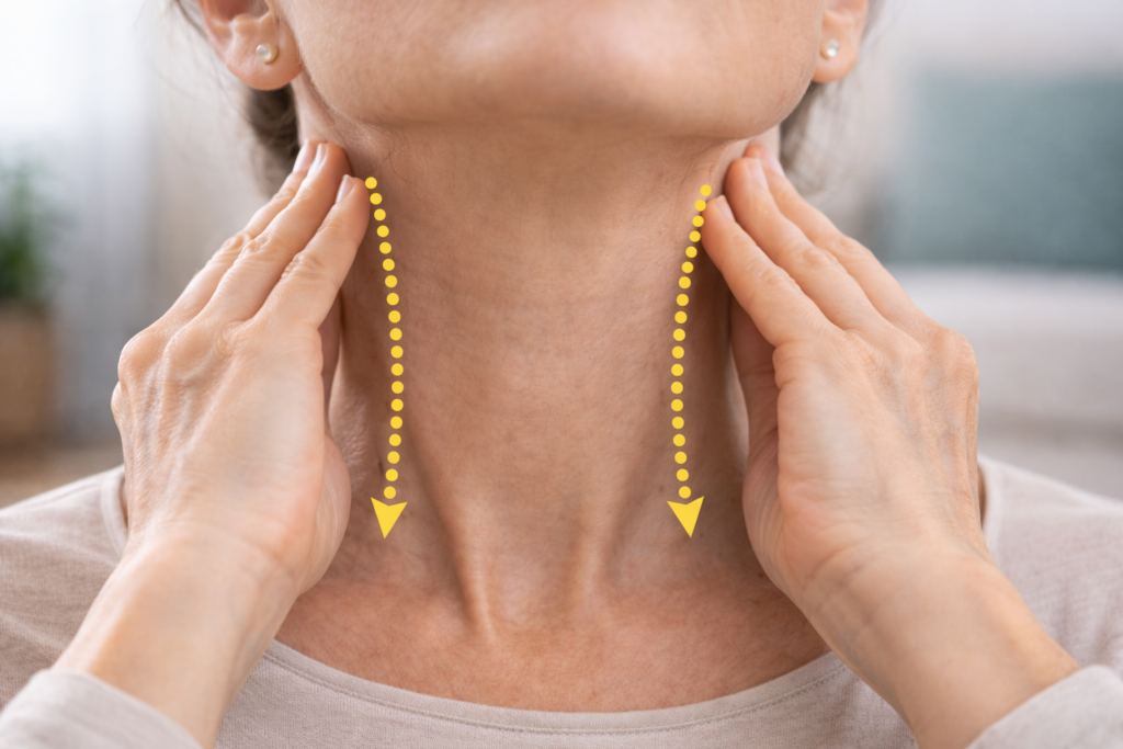 Hands demonstrating lymphatic neck drainage technique, gently sweeping from below the ears down the sides of the neck toward the collarbones to support lymph flow.